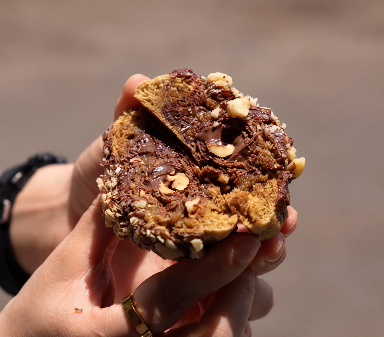 Galleta rellena de chocolate y avellanas partida a la mitad en la mano